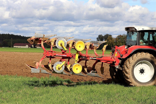 Outil agricole : charrue de labour rouge au champ